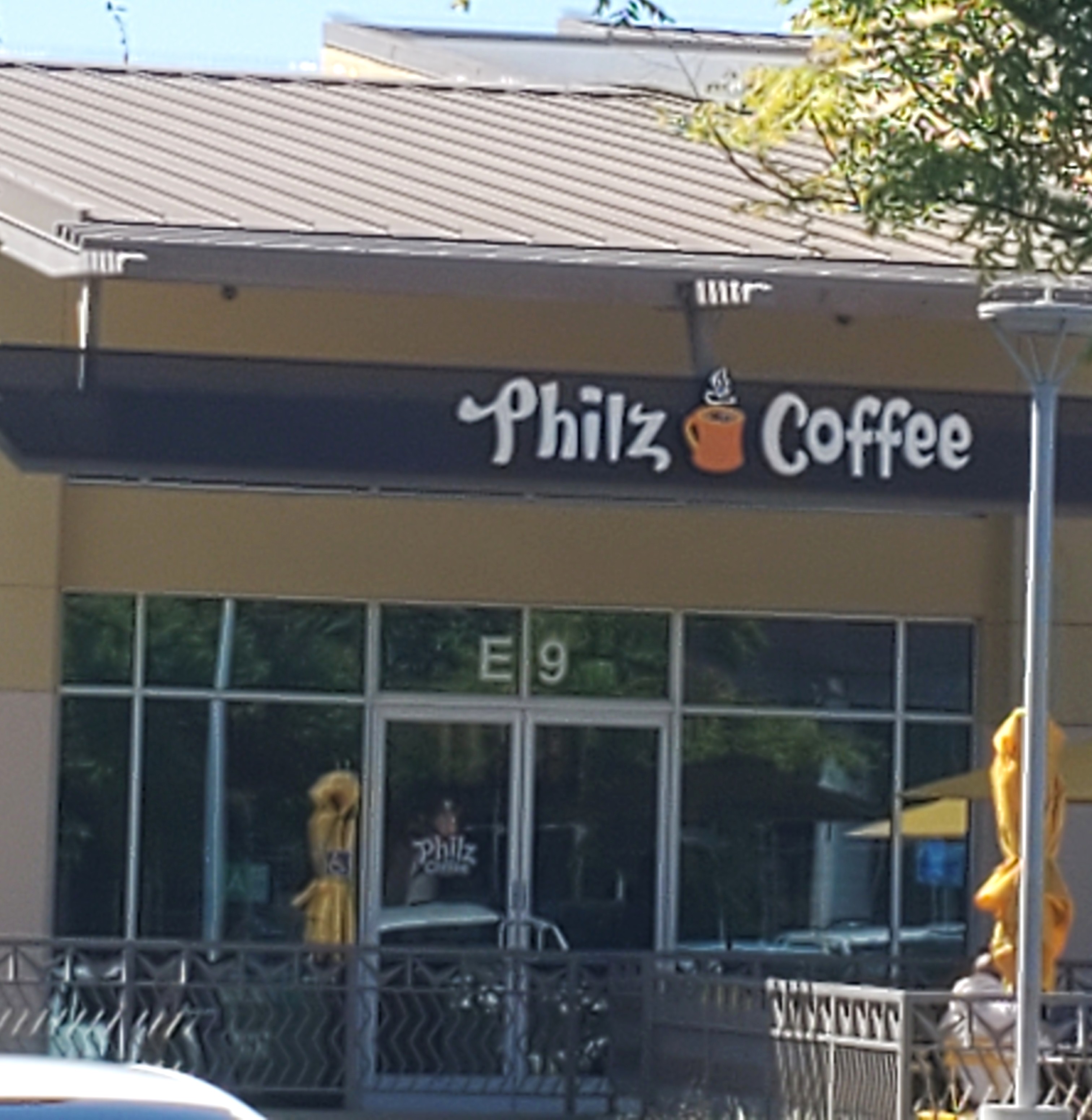 Dark brown standing seam metal roof over a Philz Coffee storefront in Coto de Caza