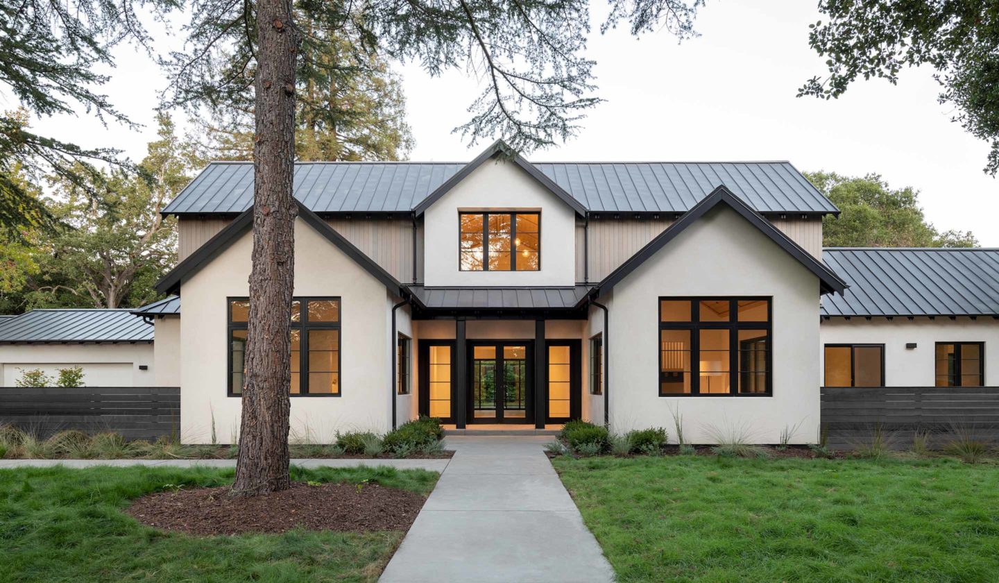 Black standing seam metal roof on a white modern farmhouse with gables and stone accents in Woodland Hills