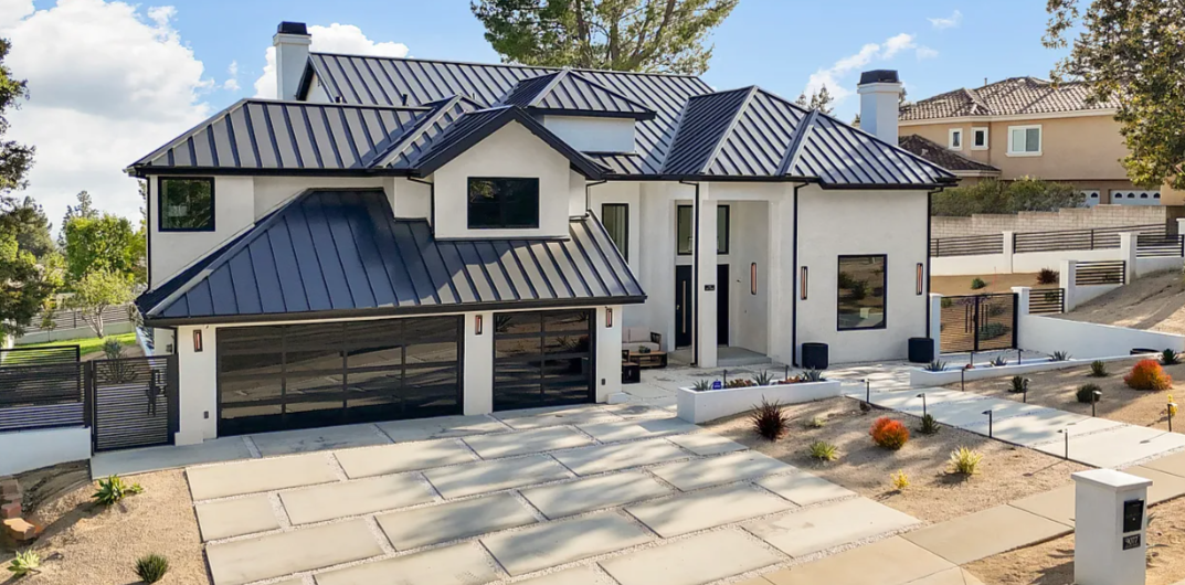 Dark standing seam metal roof on a white modern farmhouse with a glass garage door in Alta Loma