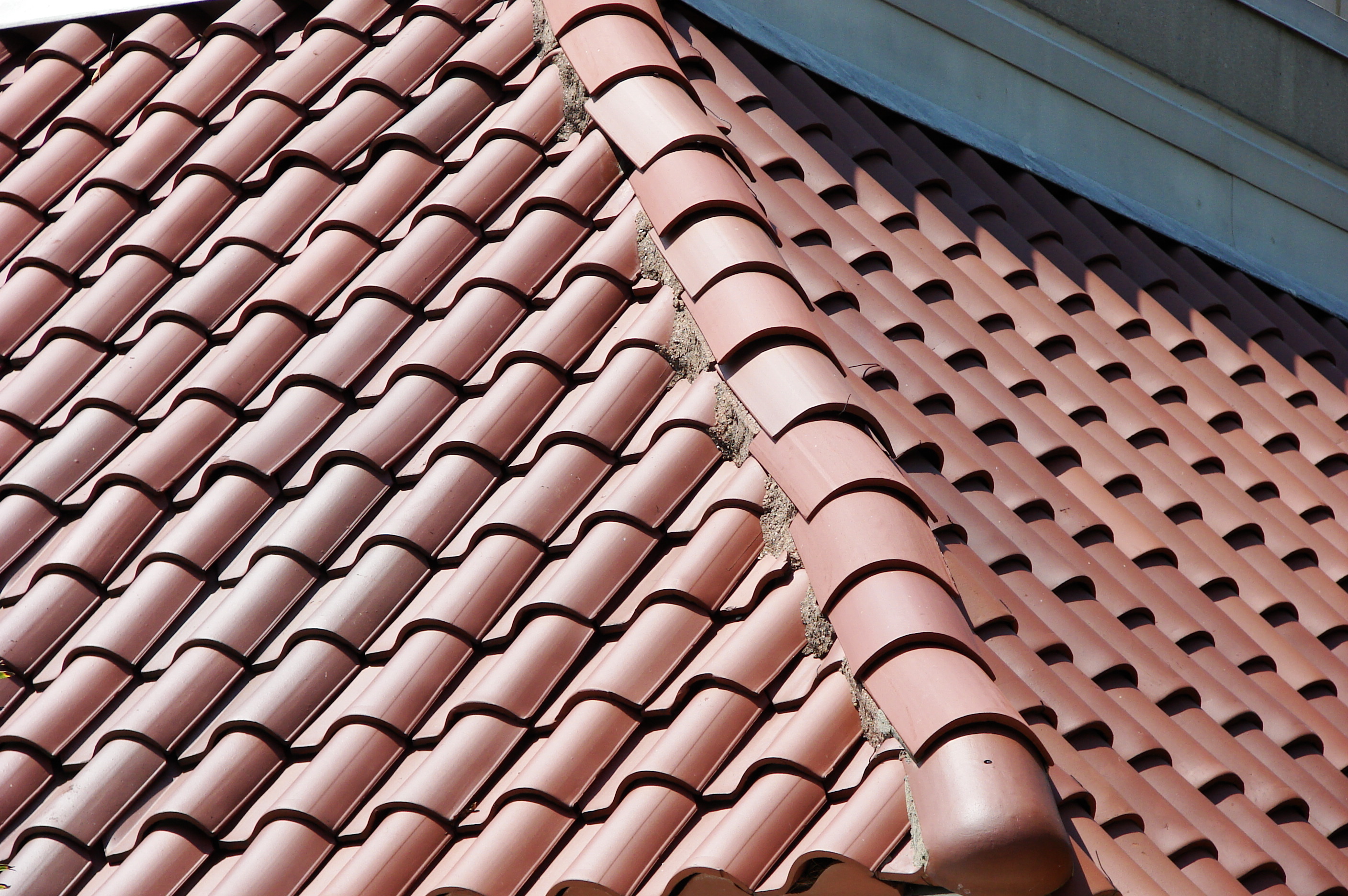 Spanish style barrel clay tile roof on a home showing uniform terracotta tiles in straight parallel rows in warm daylight