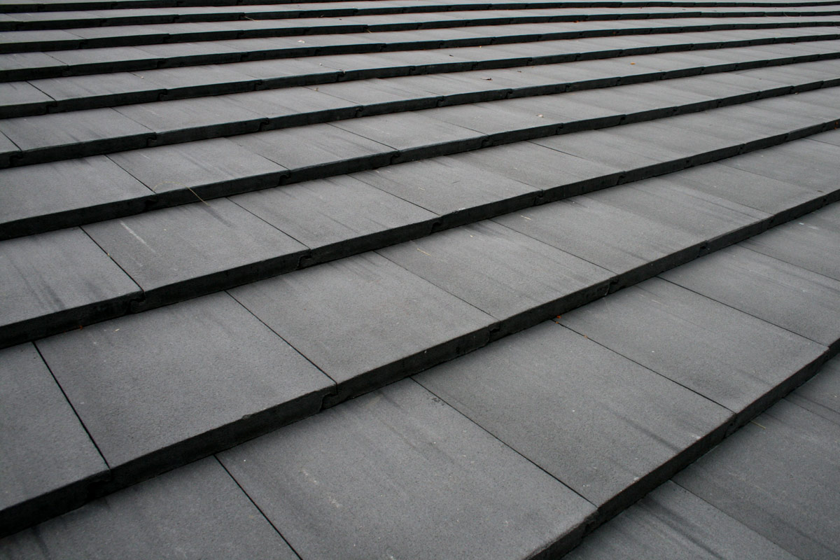 Close-up of concrete tile roofing showing flat grey concrete tiles with overlapping pattern