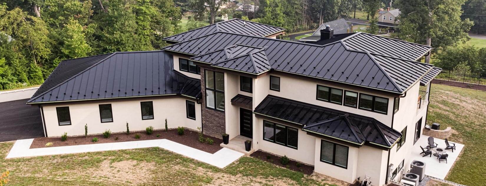 Aerial view of a large black standing seam metal hip roof on a Hidden Hills estate