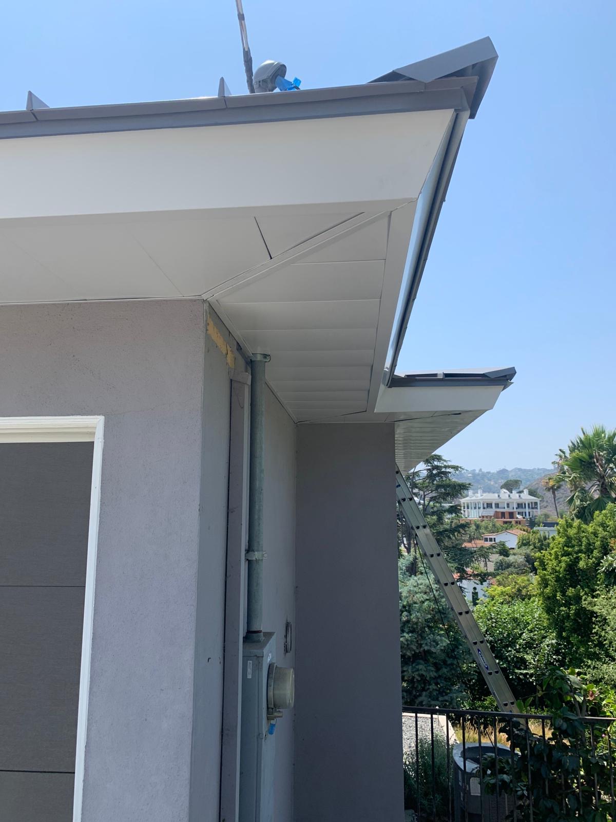 Ember-resistant metal soffit venting installed beneath the eaves of a standing seam roof.